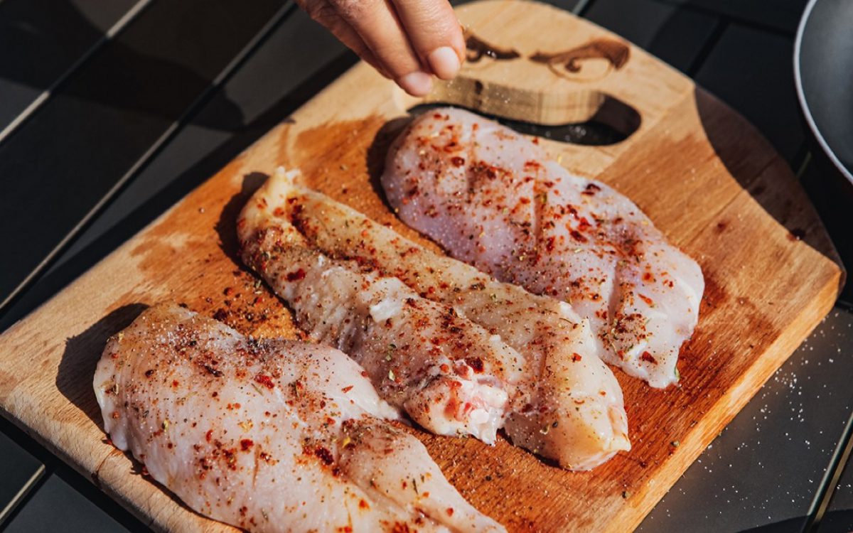 raw filets of fish with spices on cutting board