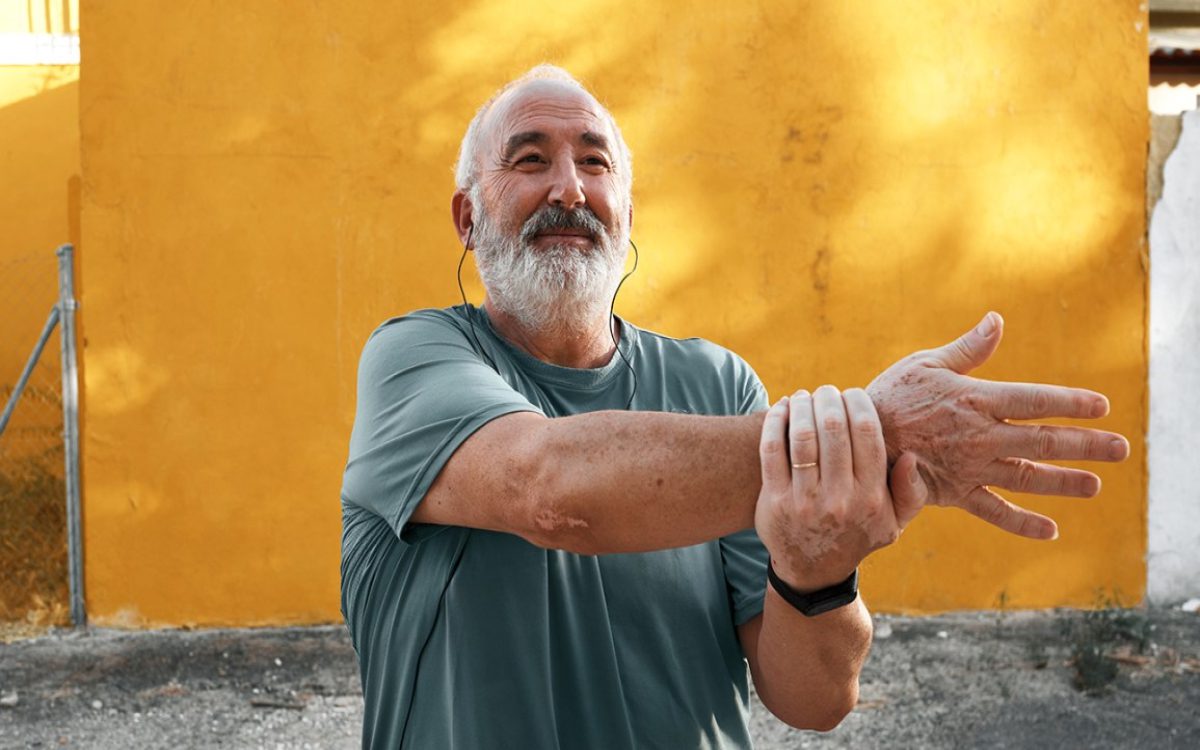 older adult exercising by stretching his arm